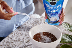Miracle-Gro mixing crystals into potting soil for improved moisture retention