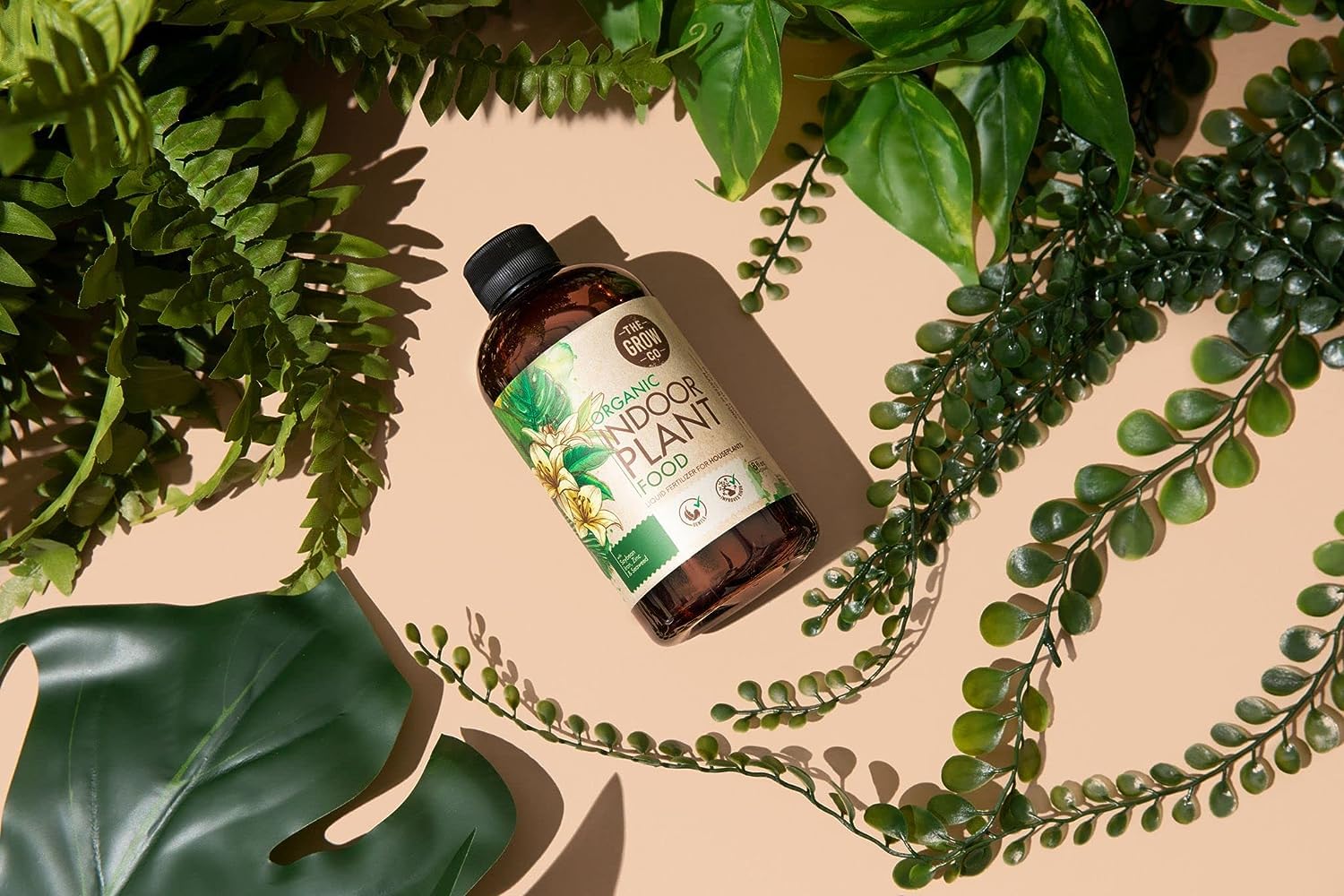 Lifestyle shelf of indoor plants with The Grow Co bottle showing practical everyday use