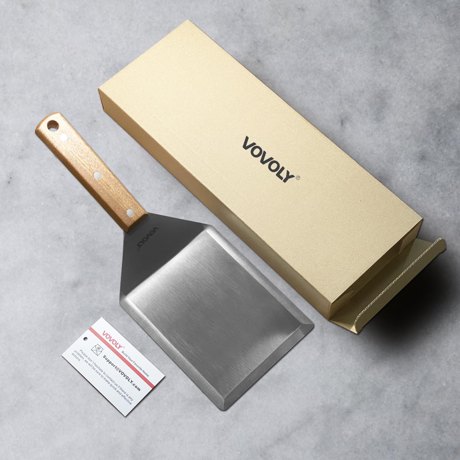 Vovoly spatula scraping griddle surface illustrating beveled edge for efficient residue removal